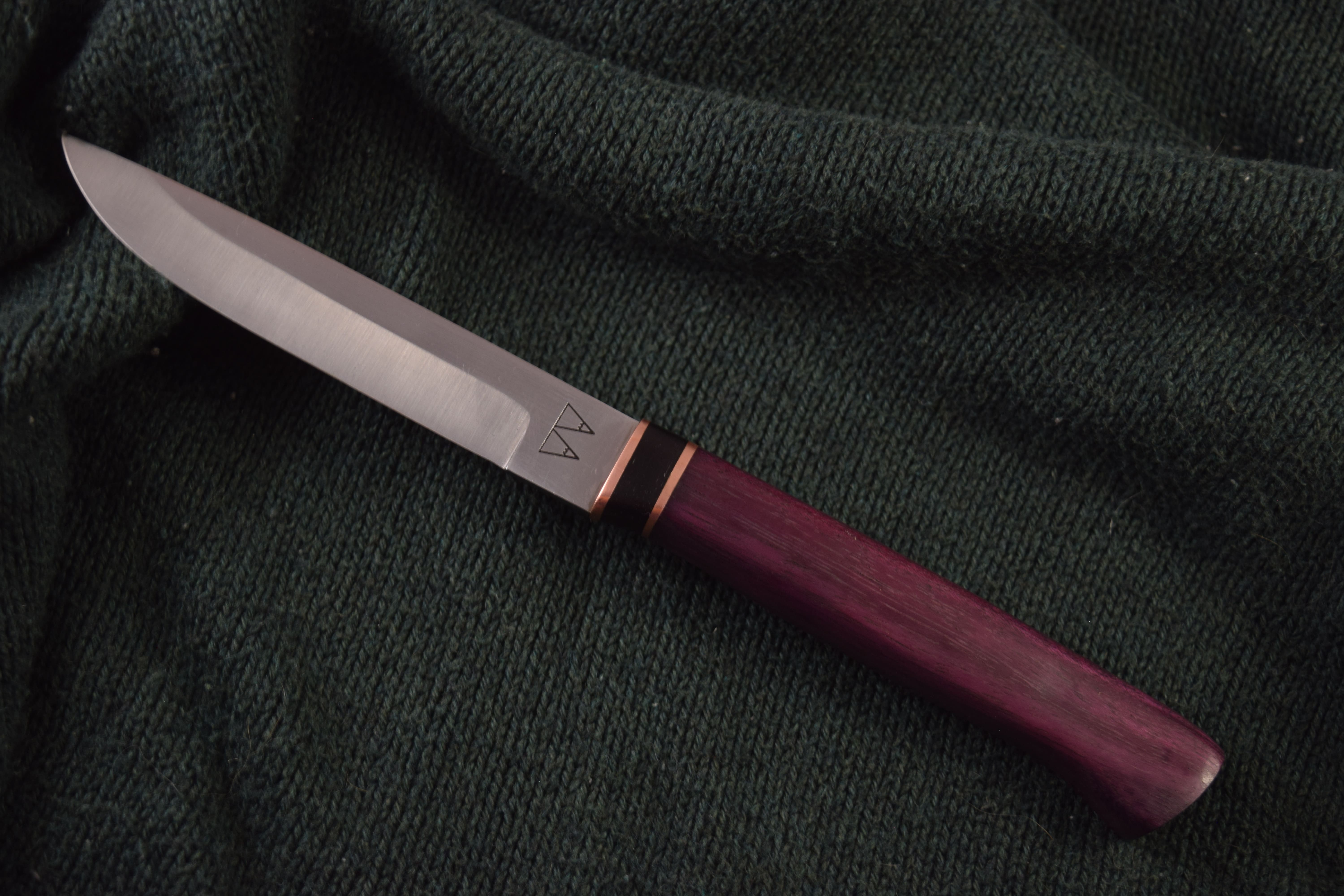 A Puukko (Traditional Finnish) knife with a Purple Heart handle and a layered Copper and Ebony bolster.