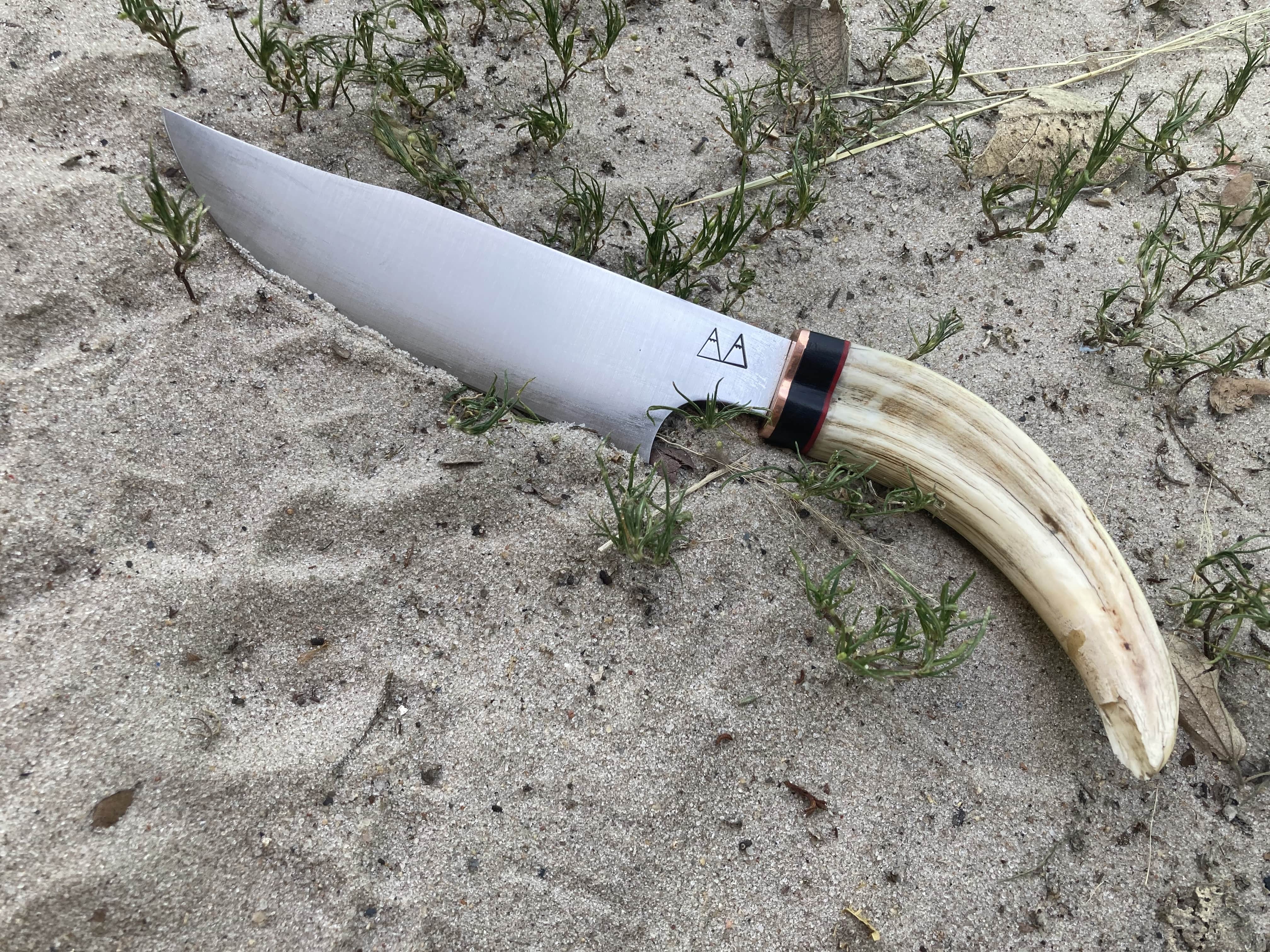 A camp chopper with a Warthog tusk handle and a copper and ebony bolster.