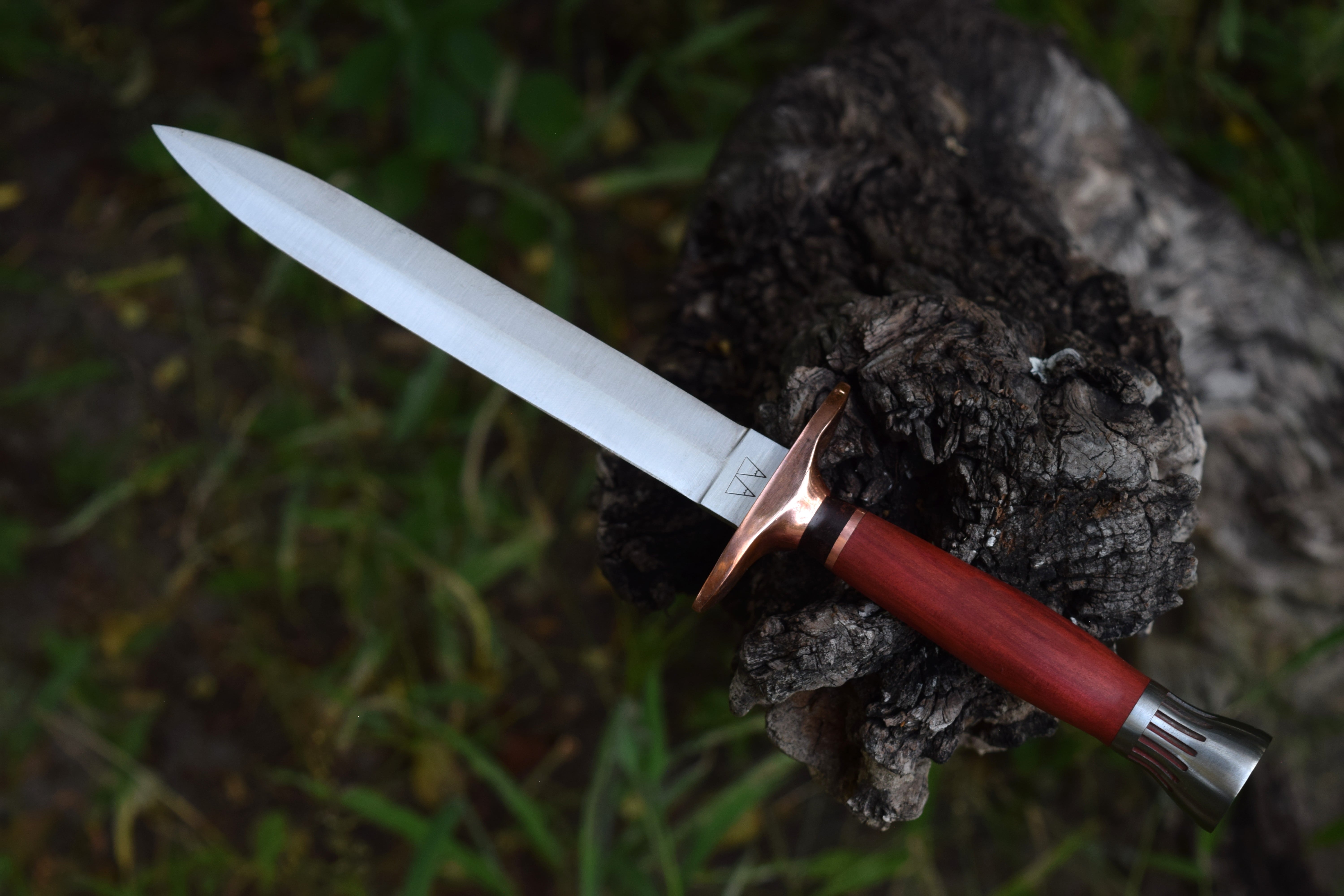 A dagger with a copper guard, Red Heart handle, and steel pommel.